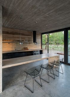 an empty kitchen and dining area with concrete walls, flooring and glass doors that open up to the outdoors