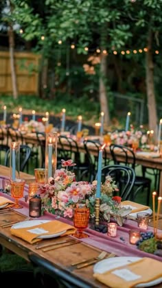 a long table with candles and flowers on it is set up for an outdoor dinner