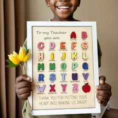 a young boy holding up a sign with letters and flowers in it that say, to my teacher you are