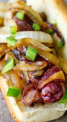 a close up of a hot dog on a bun with onions and relishes