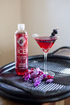 a drink sitting on top of a grill next to a glass filled with liquid and flowers