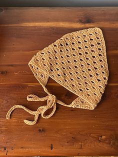 a crocheted hat sitting on top of a wooden table next to a pair of scissors