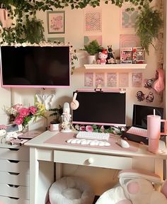 a white desk topped with two computer monitors next to a pink chair and wall mounted tv