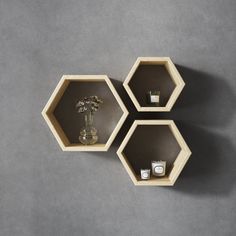 three hexagonal shelves with flowers and candles in them on a gray wall background