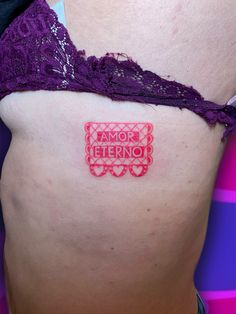 a close up of a person with a tattoo on their stomach and the word amo eferno written in red