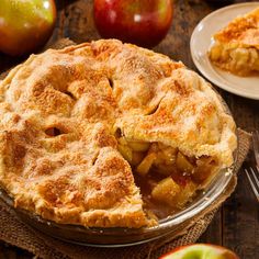 an apple pie on a wooden table with two plates and forks