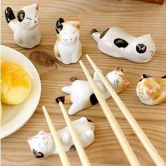 various cat figurines and chopsticks are arranged on a wooden table top