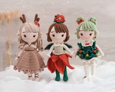 three crocheted dolls standing next to each other in the snow with christmas decorations on their heads