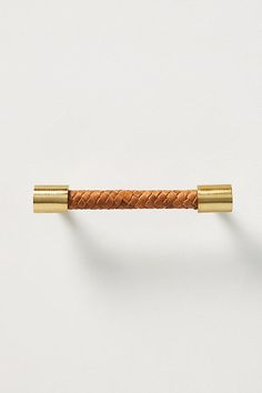 a close up of a gold handle on a white wall with a brown leather cord