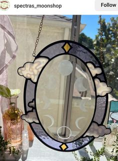 an image of a glass window with clouds and moon in the sky hanging from it's side