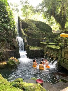 several people are in the water near a waterfall