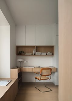 a chair sitting in front of a desk with a book shelf above it and cabinets behind it