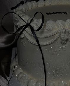 a close up of a white cake with black ribbon