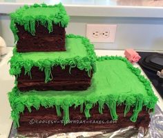 three layer chocolate cake with green icing on top, sitting on tin foil in front of a counter