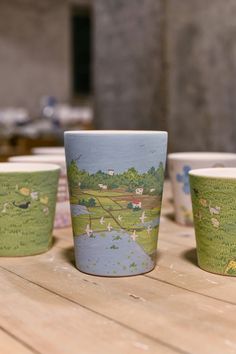 four cups sitting on top of a wooden table next to each other with animals painted on them