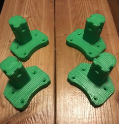 four green plastic pieces sitting on top of a wooden table next to each other with holes in them