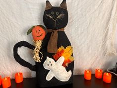 a black cat sitting on top of a wooden table next to candles and pumpkins