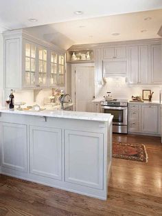 a large kitchen with white cabinets and wood floors