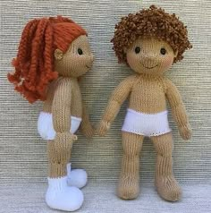 two knitted dolls sitting next to each other on a white surface, one with red hair and the other without