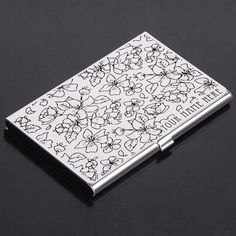 a black and white flowered business card case on a black surface with the words little flowers printed on it