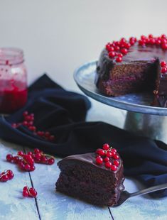 a slice of chocolate cake on a plate with cranberry toppings and a fork