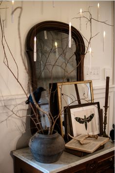 there is a vase with branches in it and candles on the table next to it