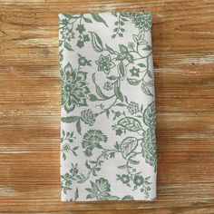 a white and green floral napkin on a wooden table