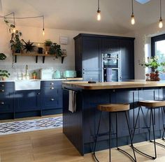 a kitchen with blue cabinets and stools next to an island in front of a window