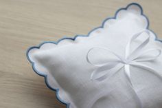 a white and blue pillow with a bow on the front sitting on a wooden table