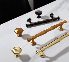 three different handles and knobs on a white marble counter top with gold hardware,