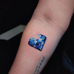 a small blue diamond tattoo on the arm