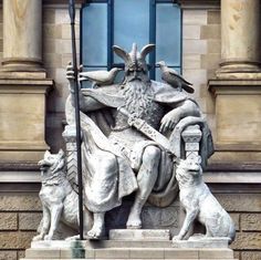 a statue of a man sitting on top of a chair with two dogs next to him