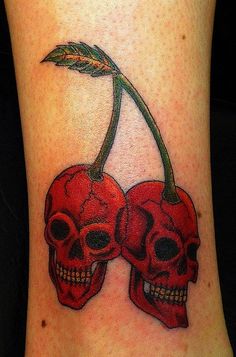 two skulls with cherries on their legs, one is red and the other is black