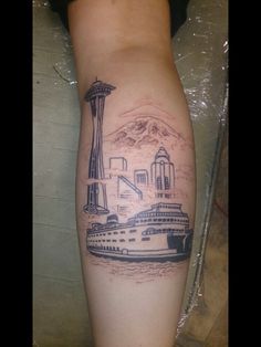 a woman's leg with a tattoo of a cruise ship and the space needle