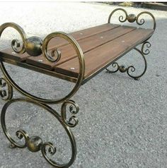 a metal and wood bench sitting on top of a cement ground next to a street