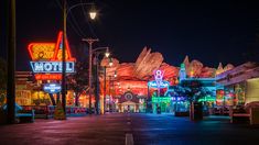 an empty city street at night with neon signs and lights on the buildings in the background