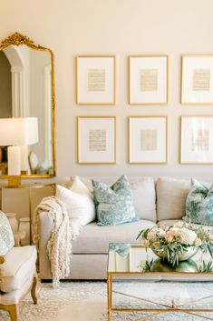 a living room filled with white furniture and pictures on the wall above it's coffee table