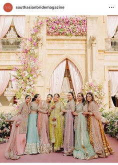 a group of women standing next to each other in front of a flower covered building