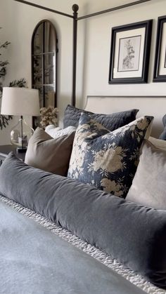 a bed with blue and white pillows in a bedroom next to two framed pictures on the wall