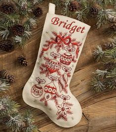 an embroidered christmas stocking with the word bridget on it and pine cones around it