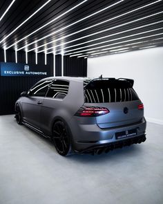 the back end of a gray volkswagen golf gtr in a showroom with lights on