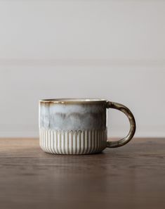 a coffee cup sitting on top of a wooden table next to a white and gray wall