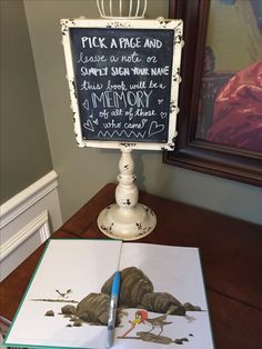 an open book sitting on top of a wooden table next to a chalkboard sign