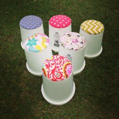 four white buckets with different designs on them sitting in the middle of some grass