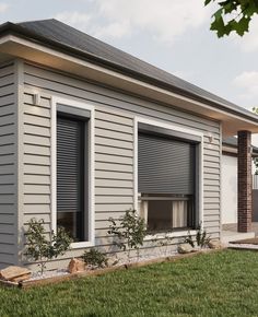 a gray house with two windows and green grass