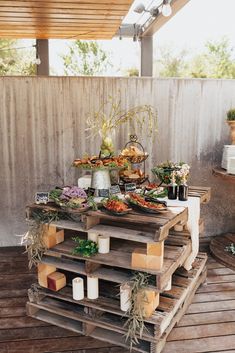 a wooden table topped with lots of food on top of a wooden floor next to a wall