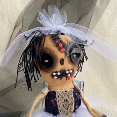 a stuffed animal doll wearing a dress and headdress with black eyes, nose rings and hair