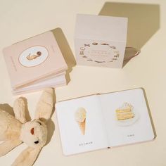 a stuffed animal next to an open book and some cards on a table with other items