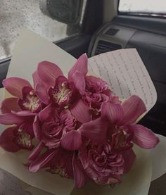 a bouquet of pink flowers sitting on top of a table next to a car window