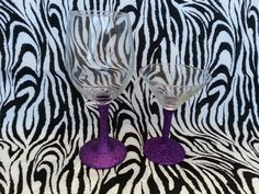 two wine glasses sitting on top of a zebra print table cloth